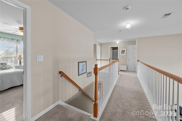 hall with an upstairs landing, visible vents, and light carpet