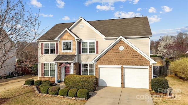 view of front facade with a shingled roof, brick siding, concrete driveway, and fence