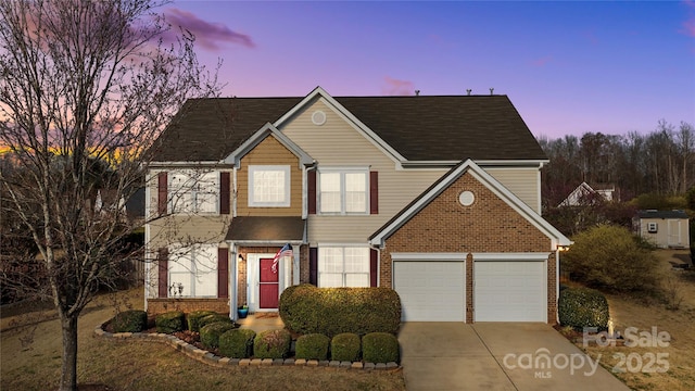 traditional home with concrete driveway, an attached garage, brick siding, and a shingled roof