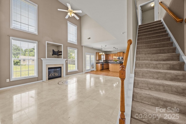 252 Legend Dr, Rock Hill, SC 29732 - unfurnished living room with stairs, baseboards, a towering ceiling, ceiling fan, and a fireplace