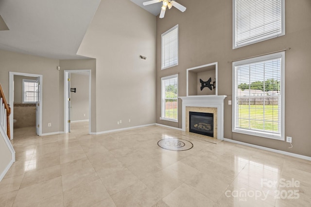 252 Legend Dr, Rock Hill, SC 29732 - unfurnished living room featuring a ceiling fan, baseboards, a fireplace, a high ceiling, and stairs