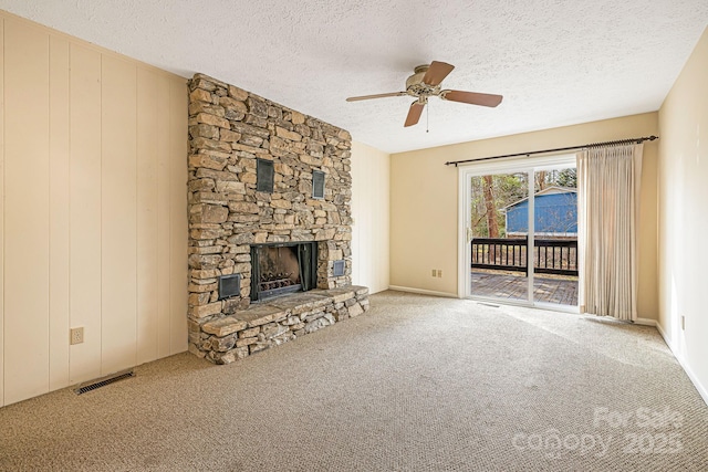 unfurnished living room with visible vents, a textured ceiling, a stone fireplace, and carpet floors