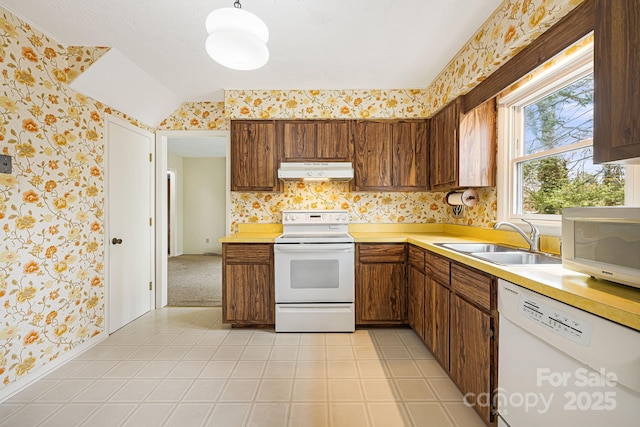 kitchen with under cabinet range hood, white appliances, wallpapered walls, and a sink