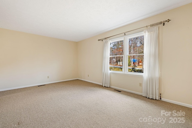 spare room featuring visible vents, baseboards, carpet, and a textured ceiling