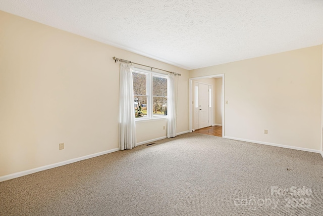 empty room with visible vents, a textured ceiling, baseboards, and carpet floors