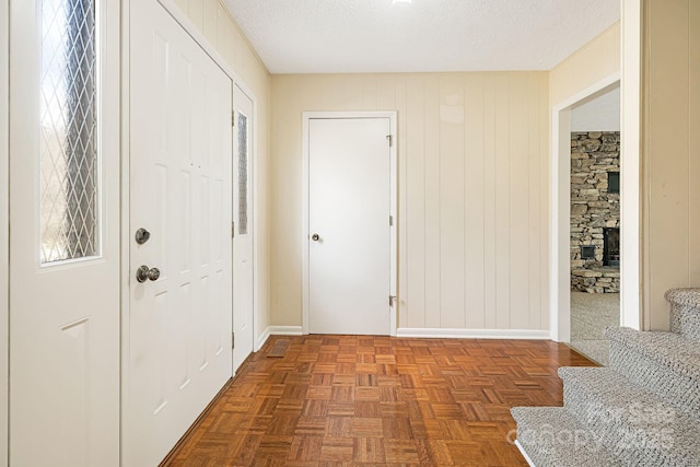 foyer with stairway, baseboards, a textured ceiling, and a fireplace