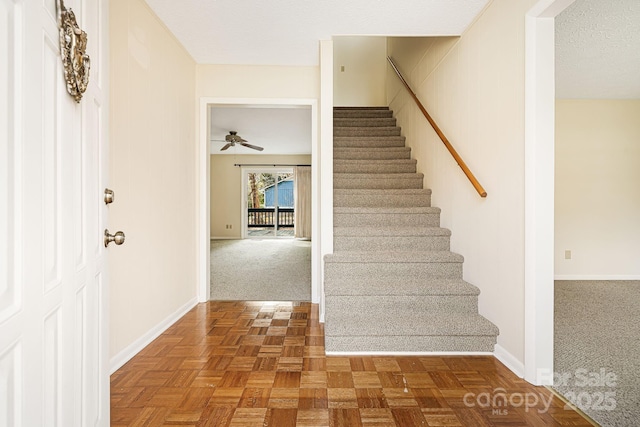 stairway with a textured ceiling, carpet, and baseboards