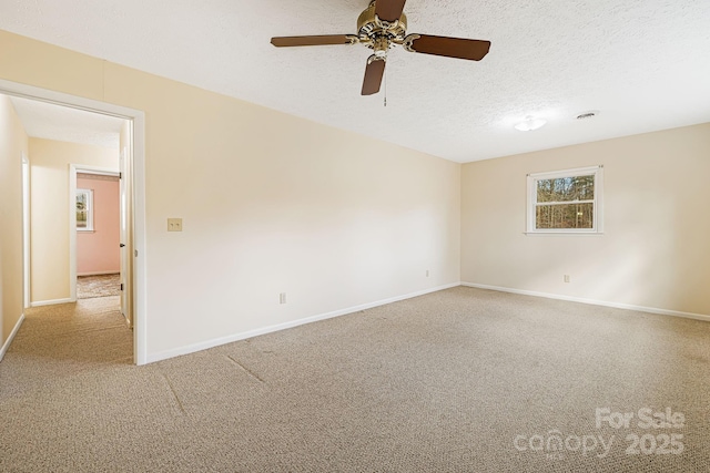 carpeted empty room featuring visible vents, a textured ceiling, baseboards, and a ceiling fan