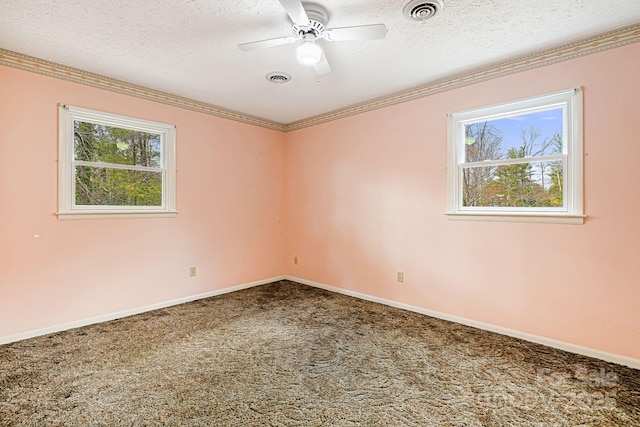 carpeted spare room with ornamental molding, a healthy amount of sunlight, visible vents, and a textured ceiling