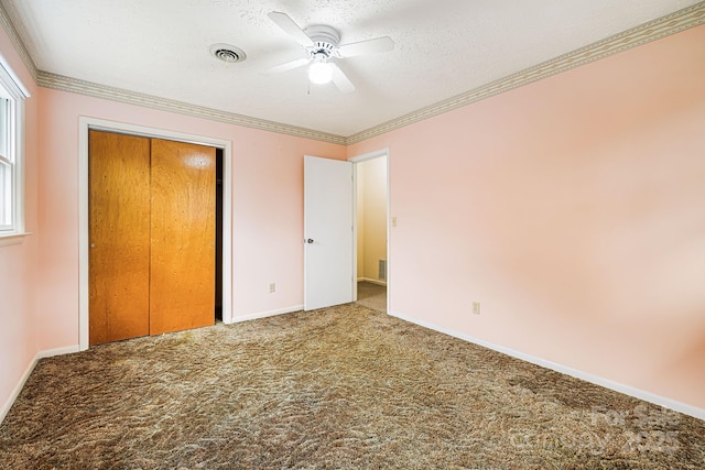 unfurnished bedroom with visible vents, a closet, a textured ceiling, crown molding, and carpet flooring