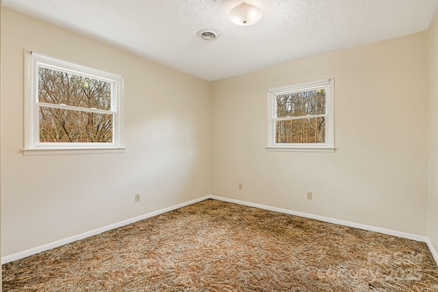 carpeted spare room featuring visible vents, baseboards, and a textured ceiling