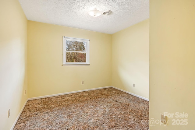 carpeted spare room with baseboards, visible vents, and a textured ceiling