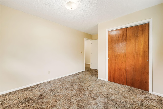 unfurnished bedroom with a closet, carpet flooring, a textured ceiling, and baseboards