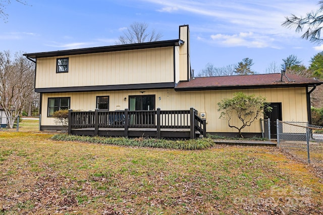 view of front of house featuring a chimney, a lawn, a wooden deck, and fence