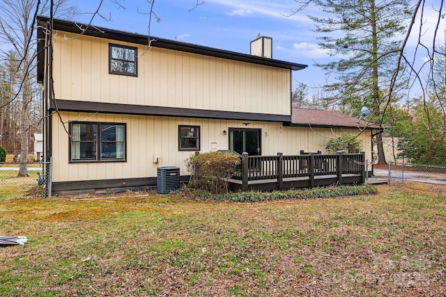 back of house featuring a lawn, a deck, central AC, fence, and a chimney