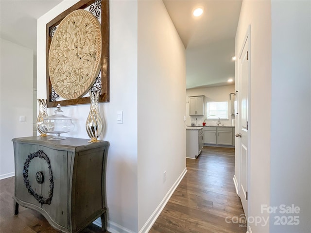 hallway with a sink, baseboards, wood finished floors, and recessed lighting