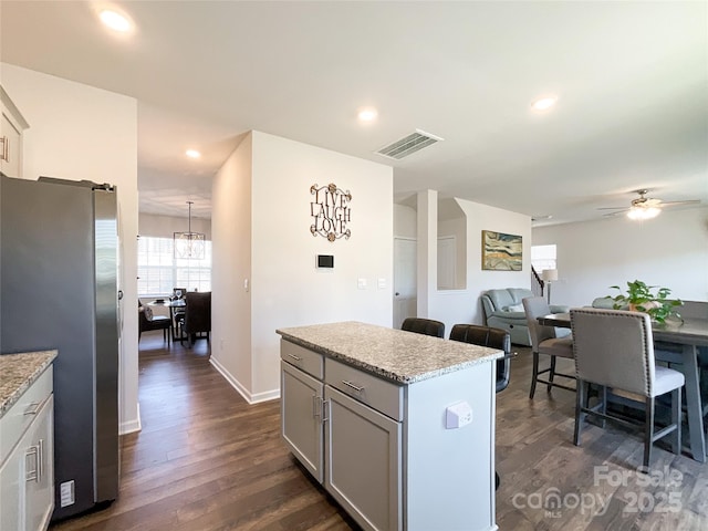 kitchen featuring visible vents, dark wood-type flooring, a kitchen island, freestanding refrigerator, and recessed lighting