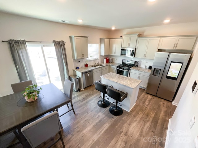 kitchen featuring visible vents, stainless steel appliances, a kitchen bar, and light wood-style floors