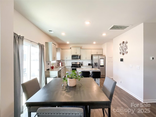 dining space with recessed lighting, visible vents, baseboards, and wood finished floors