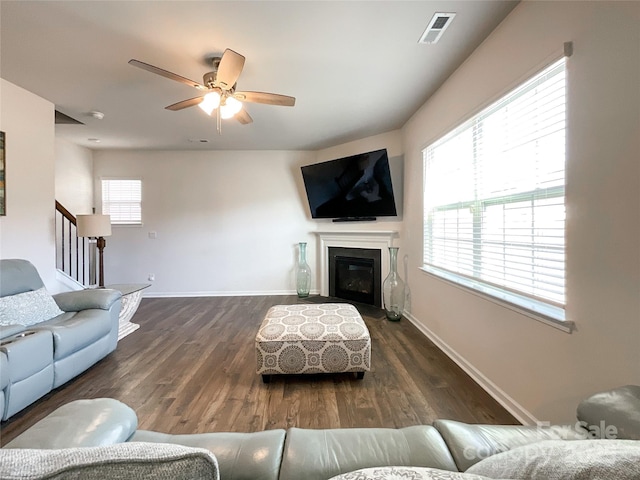 living area with stairway, wood finished floors, visible vents, baseboards, and a glass covered fireplace