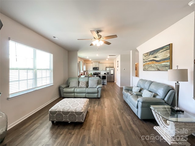 living room featuring visible vents, baseboards, dark wood-type flooring, and ceiling fan