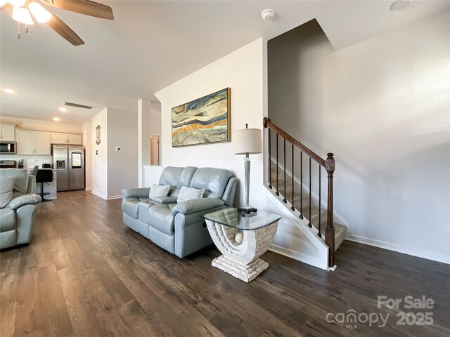 living area featuring visible vents, a ceiling fan, stairway, baseboards, and dark wood-style flooring