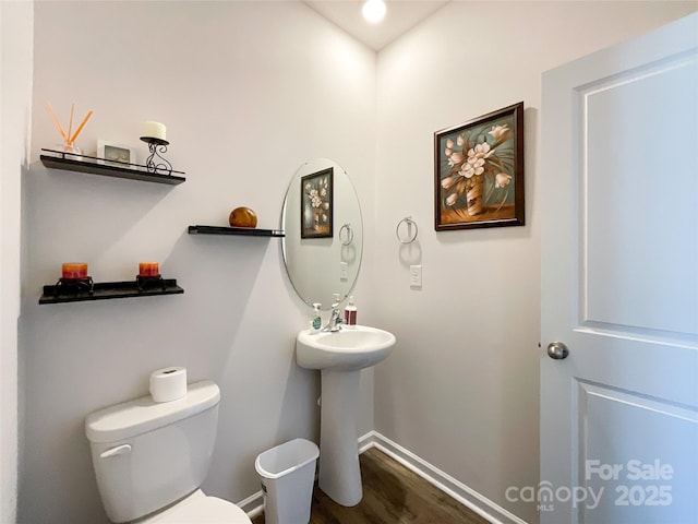 bathroom with a sink, baseboards, toilet, and wood finished floors