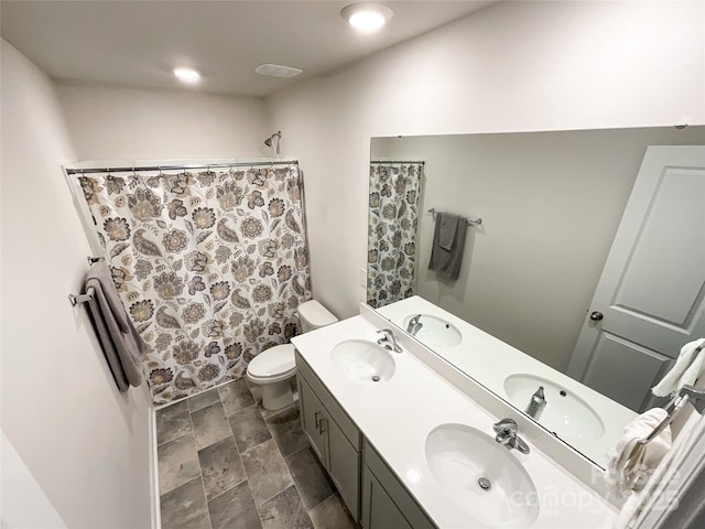 full bathroom with double vanity, toilet, and a sink