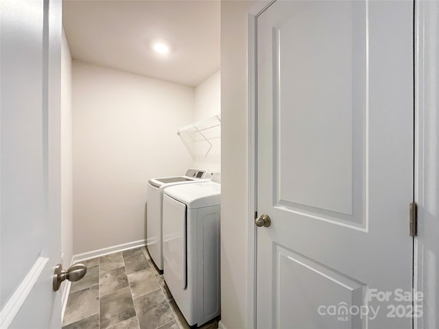 washroom featuring laundry area, stone finish floor, baseboards, and washer and clothes dryer