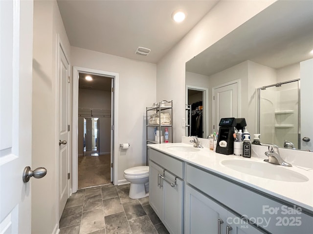 bathroom featuring a sink, visible vents, a walk in closet, and a shower stall