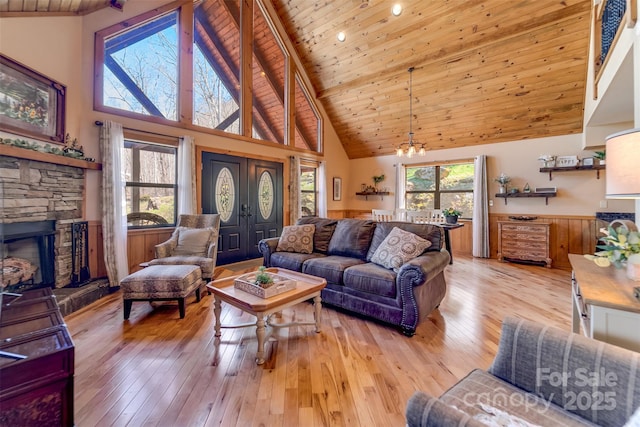 living area featuring a wainscoted wall, an inviting chandelier, wood ceiling, and light wood-type flooring