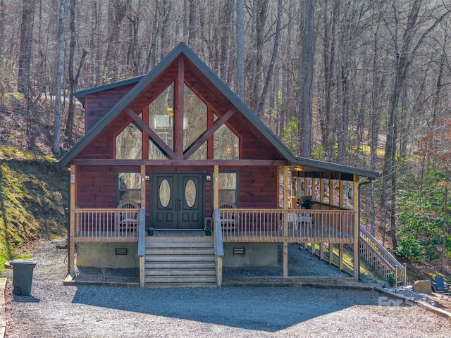 chalet / cabin featuring crawl space, a porch, a forest view, and stairs