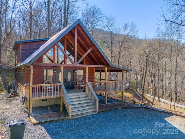 rustic home with central air condition unit, a wooded view, and crawl space