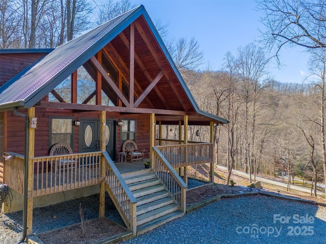 view of front of home with a deck, a wooded view, and metal roof