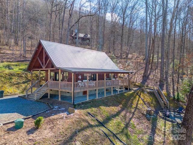 back of property featuring a lawn, a forest view, metal roof, crawl space, and stairs