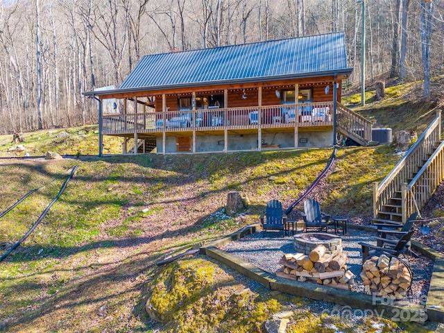 rear view of property featuring central AC unit, a wooden deck, an outdoor fire pit, stairs, and metal roof