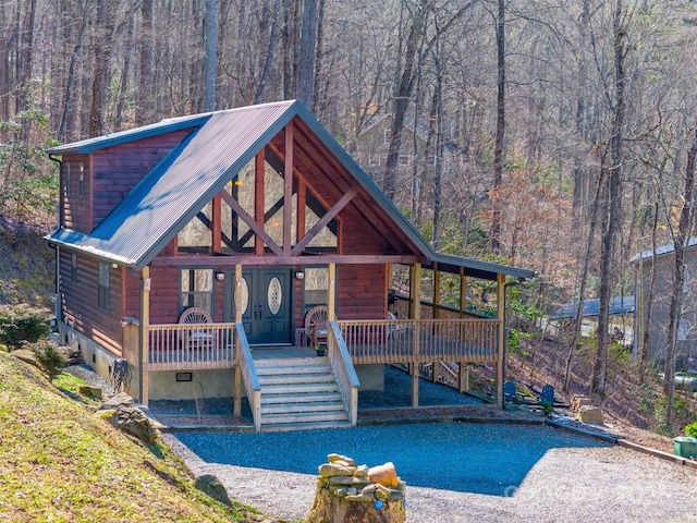 chalet / cabin with crawl space, covered porch, a forest view, and metal roof