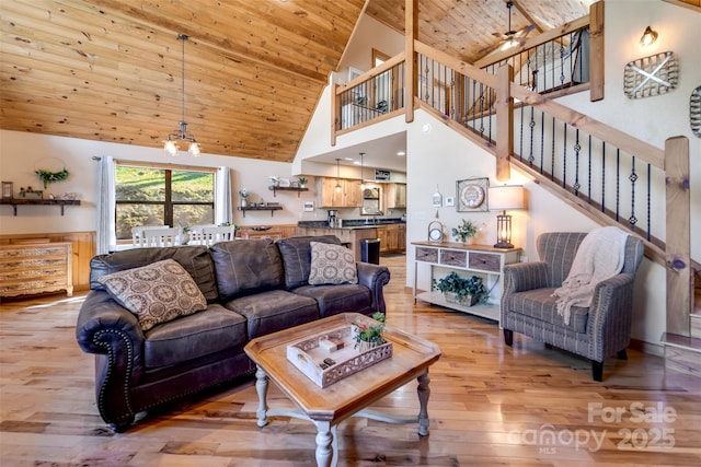 living area featuring a notable chandelier, high vaulted ceiling, light wood-style flooring, stairway, and wood ceiling