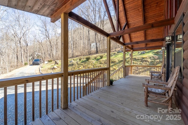 wooden terrace with covered porch and a wooded view