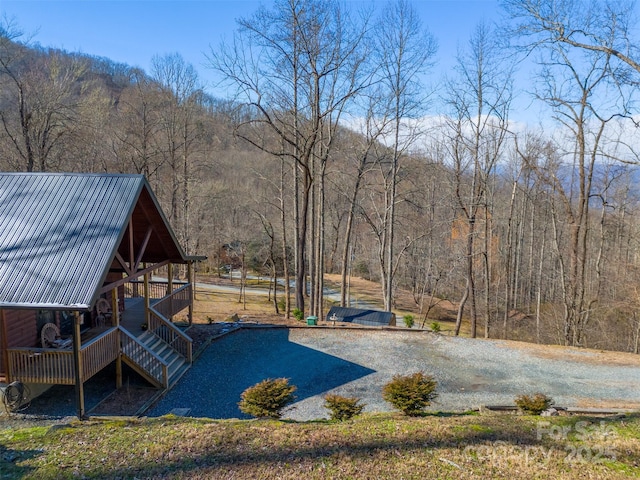 view of yard with a wooded view and gravel driveway