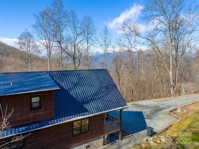 view of property exterior featuring a wooded view and metal roof