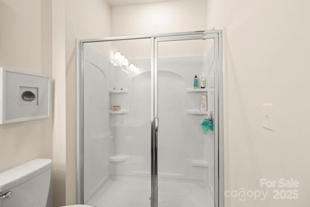 full bath featuring a shower stall and toilet