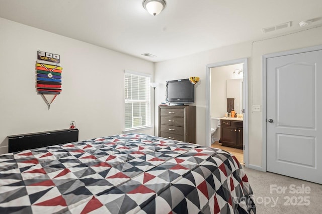 bedroom featuring visible vents, light colored carpet, and ensuite bathroom