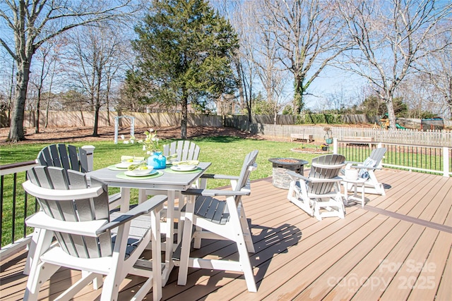 deck featuring a fenced backyard, an outdoor fire pit, outdoor dining area, and a yard