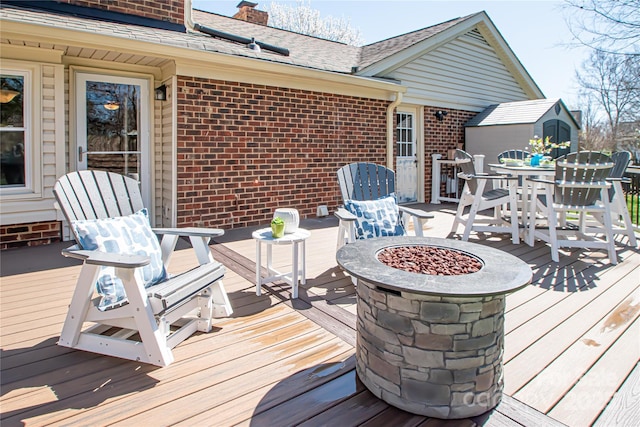 wooden deck featuring outdoor dining space and an outdoor fire pit