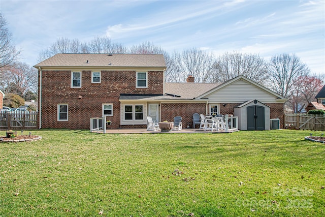 back of house featuring a storage shed, a fenced backyard, brick siding, and an outdoor structure