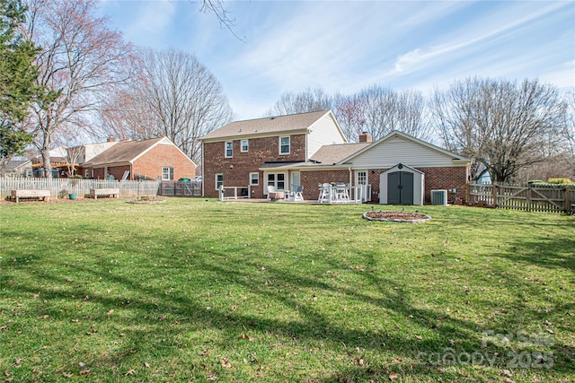 back of house featuring brick siding, a fenced backyard, a storage shed, and an outbuilding