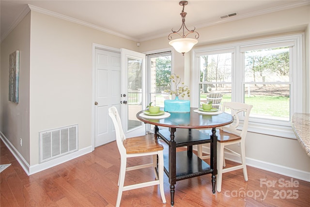 dining space featuring crown molding, light wood-style floors, visible vents, and a healthy amount of sunlight