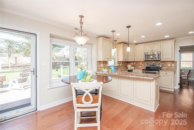 kitchen featuring backsplash, light stone counters, light wood-style floors, and appliances with stainless steel finishes