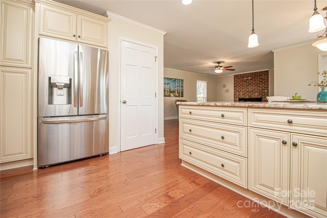 kitchen with a ceiling fan, light wood finished floors, ornamental molding, cream cabinetry, and stainless steel fridge